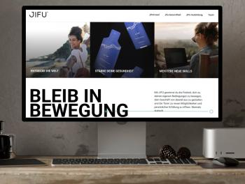Bildschirm mit geöffneter JIFU-Website: Drei Bereiche „Entdecke die Welt“, „Stärke deine Gesundheit“ und „Meistere neue Skills“ visualisieren Reisen, Produkte und Weiterbildung. Darunter der Slogan Bl